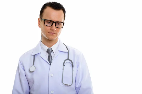 Studio shot of young sad man doctor thinking while looking down — Stock Photo, Image