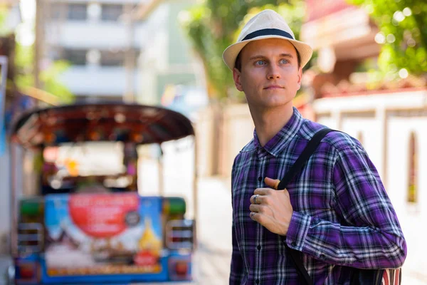 Young handsome tourist man thinking and looking at distance whil — Stock Photo, Image