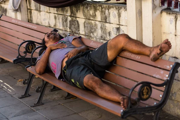 Άστεγος κοιμάται ειρηνικά στον ξύλινο πάγκο στο ταϊλανδικό Μπανγκόκ — Φωτογραφία Αρχείου