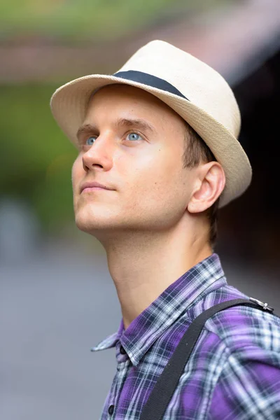 Gesicht eines jungen gutaussehenden Touristenmannes, der nachdenkt und nach oben schaut, während — Stockfoto