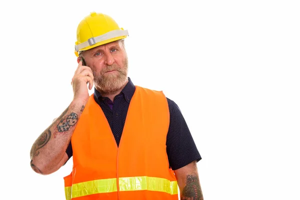 Зрілий бородатий чоловік будівельник з татуюваннями рук говорить — стокове фото