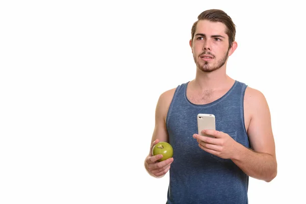 Junger schöner kaukasischer Mann mit Handy und Apfel — Stockfoto