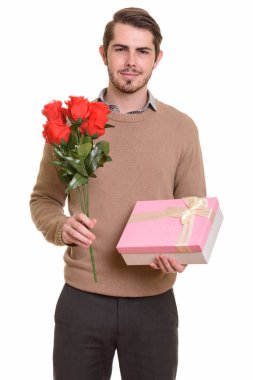 Genç yakışıklı beyaz adam kırmızı gül ve hediye kutusu tutarak okumak
