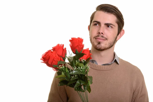 若いハンサムな白人男性再考えながら赤いバラを保持 — ストック写真