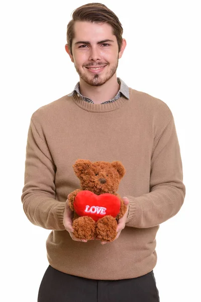 Junge hübsche kaukasische Mann hält Teddybär mit Herz und l — Stockfoto