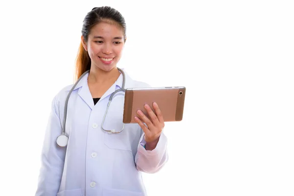 Estudio disparo de joven feliz mujer asiática médico sonriendo mientras usin —  Fotos de Stock