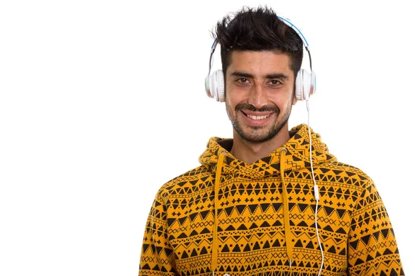 Estudio disparo de joven feliz persa hombre sonriendo mientras escucha t —  Fotos de Stock