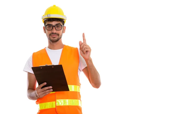 Studio shot of young Persian man construction worker holding cli — Stock Photo, Image