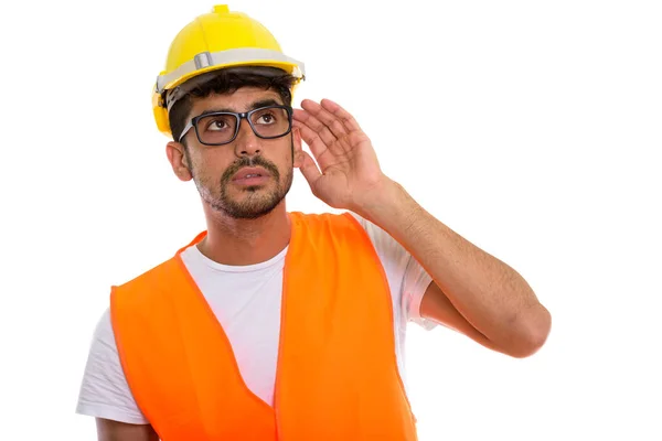 Studio shot of young Persian man construction worker listening w — Stock Photo, Image