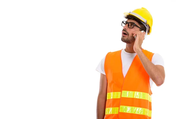 Studio shot of young Persian man construction worker talking on — Stock Photo, Image