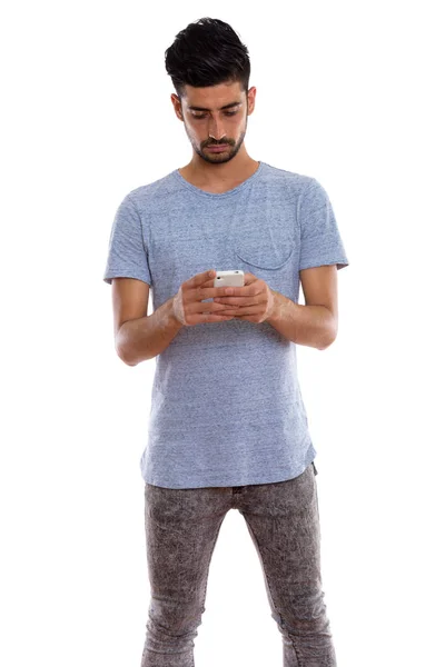 Studioaufnahme eines jungen persischen Mannes im Stehen, während er Handy benutzt — Stockfoto