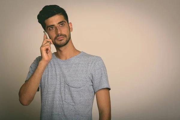 Studioaufnahme eines jungen persischstämmigen Mannes, der mit Handy und Handy spricht — Stockfoto