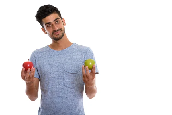 Jovem persa homem pensando enquanto segurando maçã vermelha e app verde — Fotografia de Stock