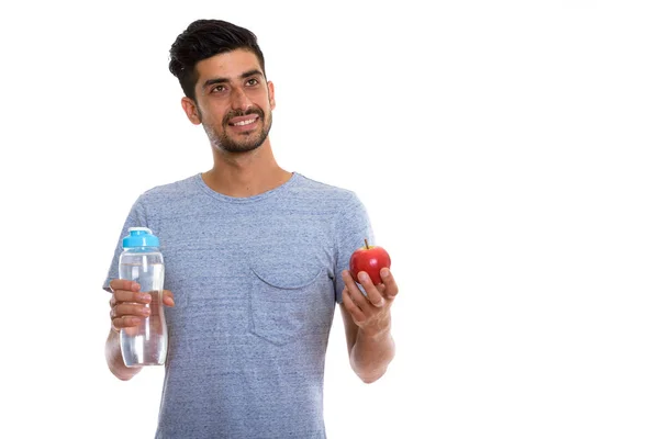 Pensativo hombre persa feliz sonriendo mientras sostiene la manzana roja y — Foto de Stock