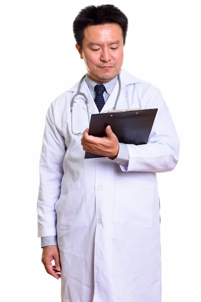 Studio shot of Japanese man doctor reading on clipboard — Stock Photo, Image