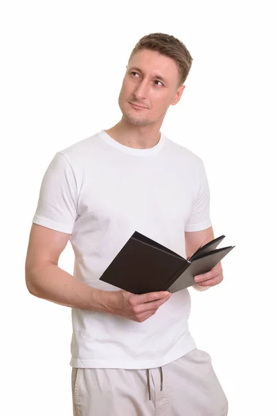 Hermoso hombre caucásico sosteniendo libro mientras piensa —  Fotos de Stock