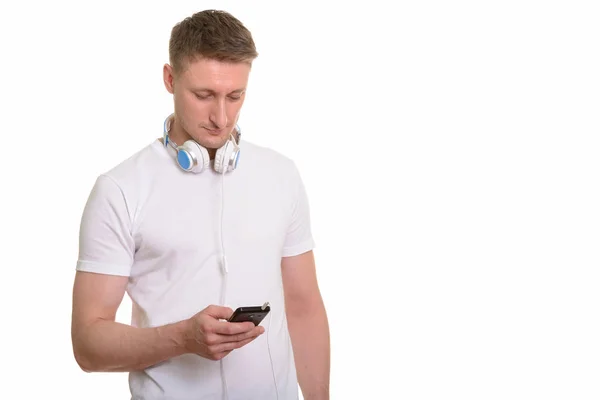 Hombre caucásico guapo usando el teléfono móvil mientras usa auriculares — Foto de Stock
