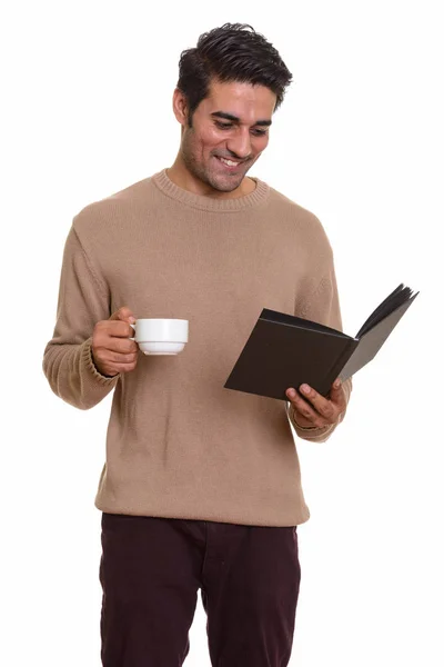 Giovane felice uomo persiano libro di lettura, mentre tenendo tazza di caffè — Foto Stock