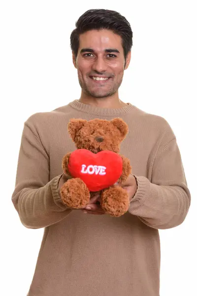 Młody szczęśliwy człowiek Perski trzyma misia z miłości i serca s — Zdjęcie stockowe