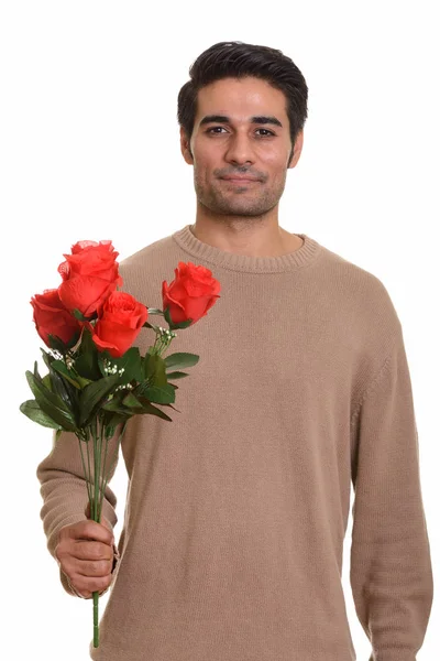 Nuori komea persialainen mies tilalla punaisia ruusuja valmis Valentine — kuvapankkivalokuva