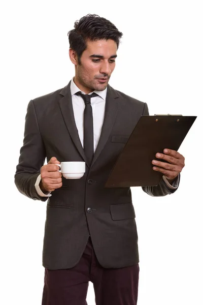Jovem bonito empresário persa segurando xícara de café enquanto lido — Fotografia de Stock