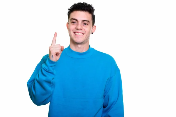 Estudio de disparo de joven feliz sonriendo y señalando con el dedo hacia arriba — Foto de Stock