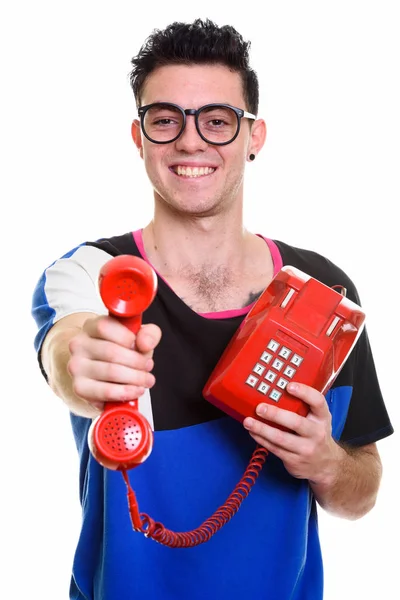 Studioaufnahme eines glücklichen jungen Mannes, der lächelt, während er alte Telefone gibt — Stockfoto