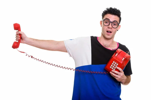 Студійний знімок молодого чоловіка, що тримає старий телефон, шокований — стокове фото