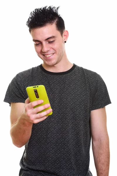 Studio skott av glad ung man ler när du använder mobiltelefon — Stockfoto