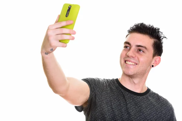 Studio shot van gelukkige jonge man die lacht terwijl het nemen van de selfie pictu — Stockfoto