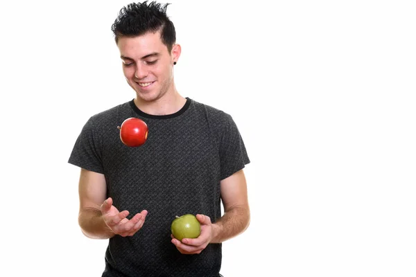 Feliz joven sonriendo mientras sostiene la manzana verde y lanza r — Foto de Stock