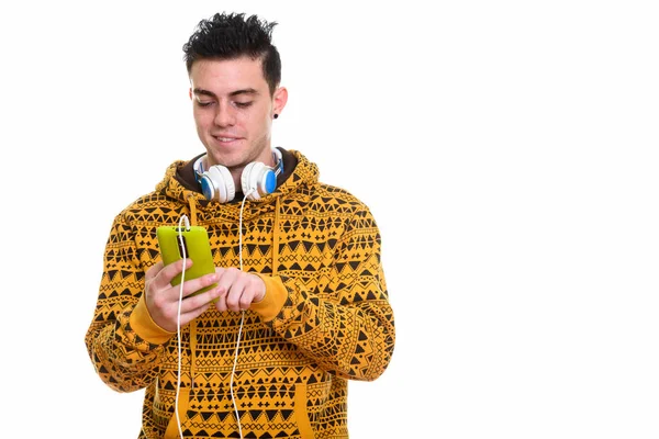 Glücklicher junger Mann lächelt und benutzt Handy, während er hea trägt — Stockfoto