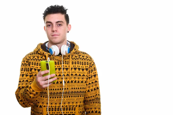 Studio shot of young man holding mobile phone while wearing head — Stock Photo, Image