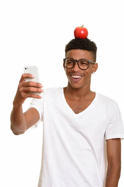 Young happy African man with apple on head while taking selfie — Stock Photo, Image