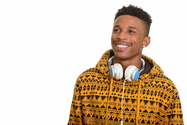 Jovem homem africano feliz usando fones de ouvido em torno do pescoço, enquanto thi — Fotografia de Stock
