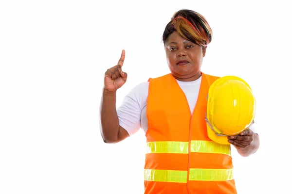 Studio shot of fat black African woman construction worker holdi
