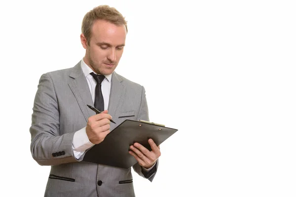 Handsome Caucasian businessman writing on clipboard — Stock Photo, Image
