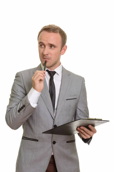 Handsome Caucasian businessman holding pen and clipboard while t — Stock Photo, Image