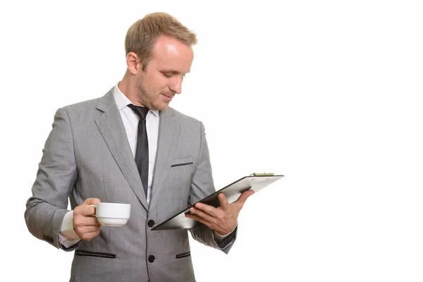 Guapo caucásico hombre de negocios leyendo portapapeles mientras bebe — Foto de Stock