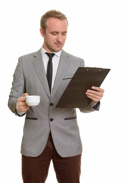 Handsome Caucasian businessman reading clipboard while drinking — Stock Photo, Image