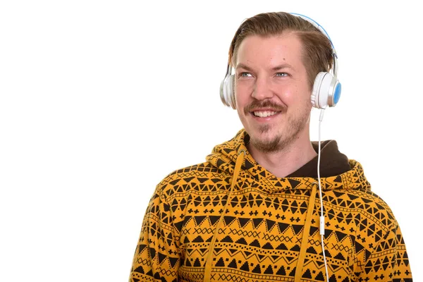 Nuori onnellinen valkoihoinen mies kuuntelee musiikkia ajatellessaan — kuvapankkivalokuva