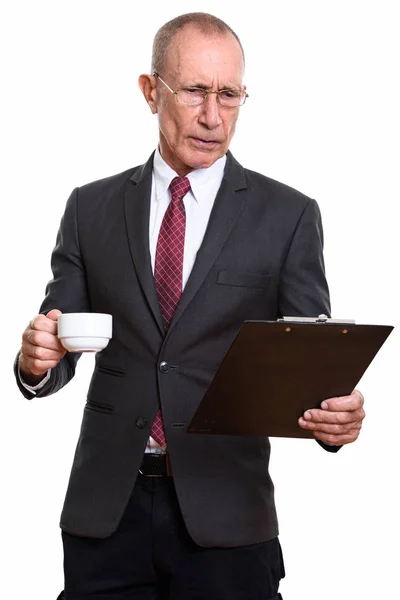 Studio shot of senior businessman reading on clipboard while hol — Stock Photo, Image