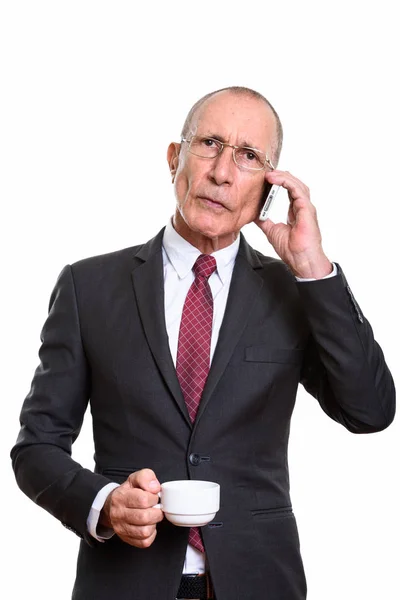Студійний знімок старшого бізнесмена, який тримає чашку кави під час талькі — стокове фото