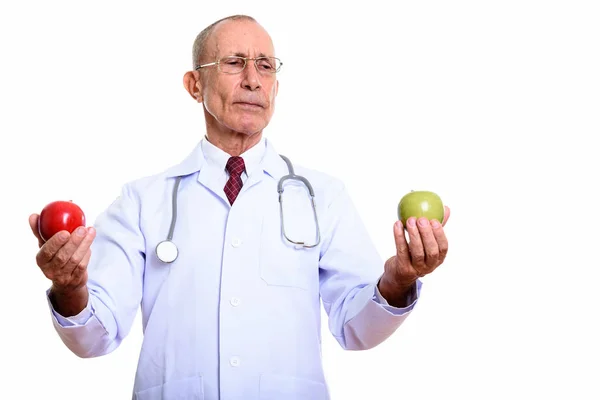 Estudio de tiro de hombre mayor médico sosteniendo manzana roja y buscando un — Foto de Stock