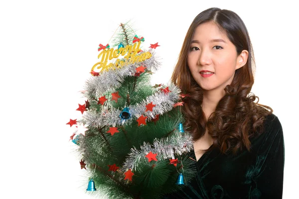 Joven feliz mujer asiática sosteniendo Feliz árbol de Navidad —  Fotos de Stock