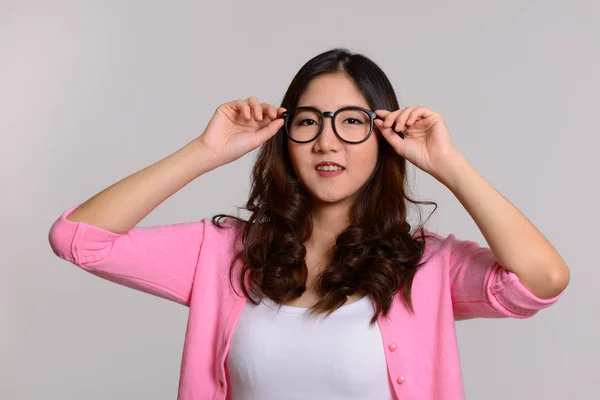 Jovem mulher asiática feliz com as mãos em óculos — Fotografia de Stock