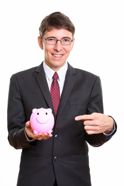 Studio shot of happy businessman smiling while holding piggy ban — Stock Photo, Image