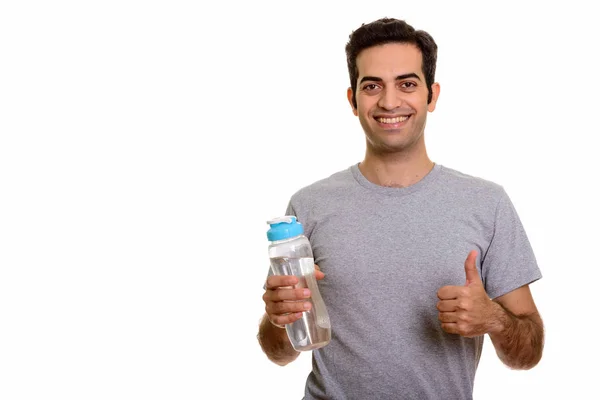 Joven hombre persa feliz sosteniendo la botella de agua y dando pulgar hacia arriba — Foto de Stock