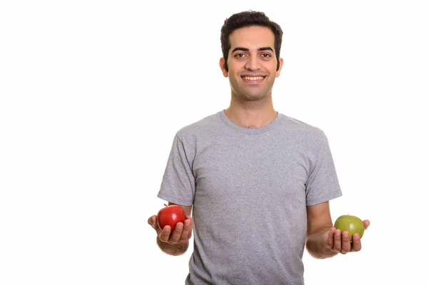 Young happy Persian man holding red and green apple ready for gy — Stock Photo, Image