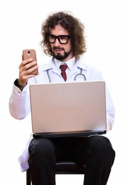 Szczęśliwy człowiek lekarz uśmiechnięty podczas korzystania z telefonu komórkowego z laptopem — Zdjęcie stockowe